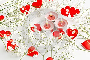 Romantic Valentines Day background. Burning candles and red hearts decorated with flowers