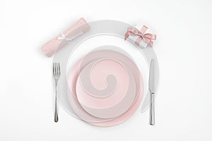 Romantic or Valentines day dinner background. Festive table setting with pink tableware, gift and napkin. Valentine`s card