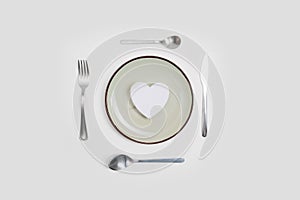 Romantic valentines day dinner idea concept. Heart on plate and silver wear on white background