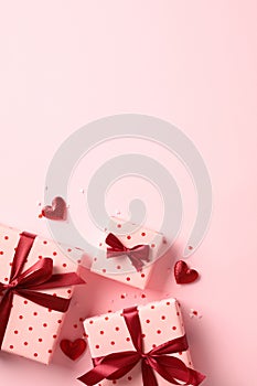 Romantic Valentines Day vertical background with gift boxes and red hearts on pastel pink table. Top view. Flat lay