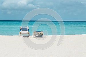 Romantic view of the Caribbean beach, two beach chairs against blue sky