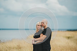 Romantic view of couple in black clothes when they embrace on the edge of the rocky coast of the Baltic sea