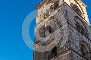 A romantic view of a Tower in Trujillo with the moon appearing in plain daylight.