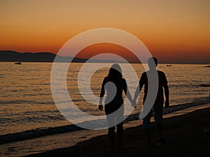 Romantic walk on the beach at sunset.