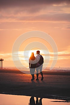 Romantic walk of a young couple on the beaches of Oostende in western Belgium at sunset. Love and devotion. Reflection in a pool