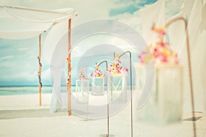 Romantic wedding ceremony on the beach, white decoration with floral decoration in vintage toned colors