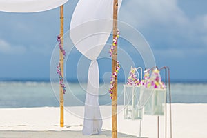 Romantic wedding ceremony on the beach, white decoration with floral decoration in vintage toned colors