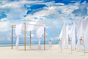 Romantic wedding ceremony on the beach, white decorations with flowers and lanterns. Romantic beach wedding