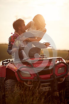 Romantic wedding couple at sunset drive quad atv vehicle