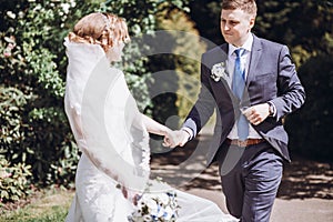 Romantic wedding moment, couple of newlyweds smiling portrait, bride and groom hug while on a walk in the park