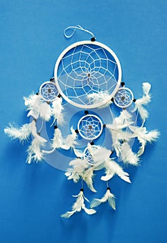 Romantic whitedreamcatcher with white feathers over plain blue isolated backround