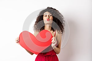 Romantic woman in dress showing big red heart, pucker lips for kiss and express love, express sympathy, white background