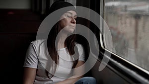romantic woman is looking at window of suburban train, travelling by railway, sitting in wagon