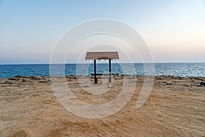 Romantic wooden bench overlooking the beautiful azure lagoon at sunset near Cape Greco.