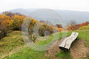 Romantic wooden bench with the view to the hills with autumn colorful forest landscape