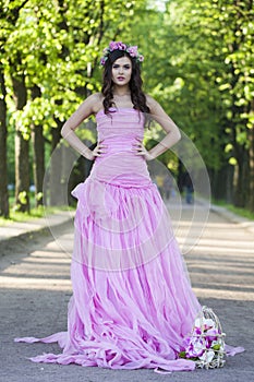 Romantic young adult lady with with long hair, make-up and pink flower in spring park. Beauty woman portrait