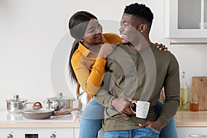 Romantic Young African American Couple Hugging And Drinking Coffee In Kitchen Interior