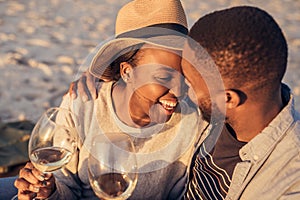 Romantic young African couple drinking wine together at the beach