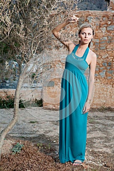 Romantic young blond woman near olive tree