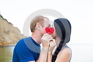 Romantic young caucasian couple kissing on the seaside hiding be