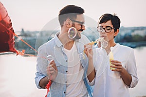 Romantic young couple dating outdoor and blowing bubbles