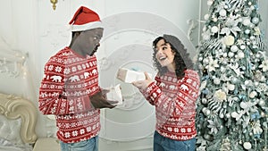 Romantic young couple exchanging Christmas gifts. Couple in love celebrating Christmas at home