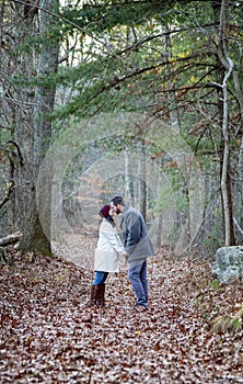 Romantic young couple holding hands and kissing in the woods