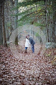 Romantic young couple holding hands and kissing in the woods