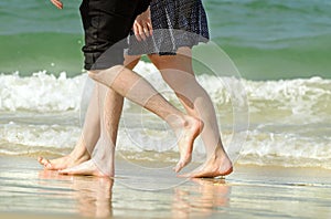 Romantic young couple on holiday walking along beach