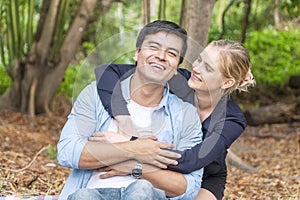 Romantic young couple hugging and laughing together while looking each other at outdoors. Cheerful woman blond hair embracing her