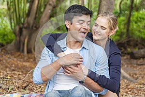 Romantic young couple hugging and laughing together while looking each other at outdoors. Cheerful woman blond hair embracing her