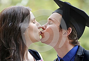 Romantic young couple kissing after man graduates university
