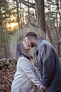 Romantic young couple kissing in the New England woods