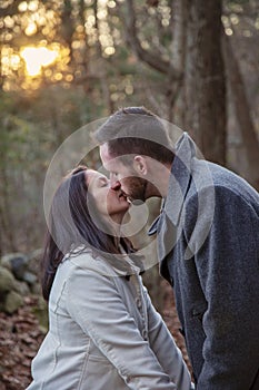 Romantic young couple kissing in the New England woods