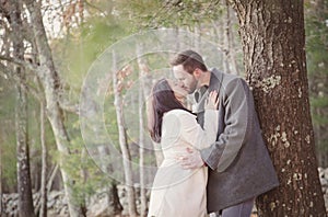 Romantic young couple kissing under a tree on a cold fall day