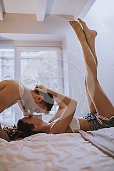 Romantic young couple laying on the bed with bodies in opposite directions while kissing