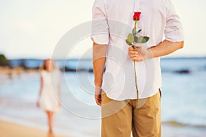 Romantic Young Couple in Love, Man holding surprise rose for beautiful young woman