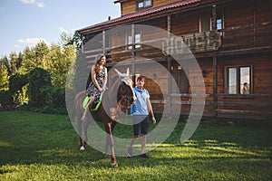 Romantic young couple in love, a walk on a horse on nature background and wooden country-style hotel. Young woman