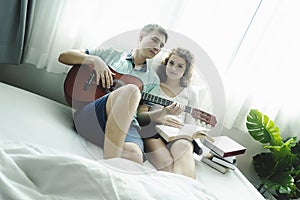 Romantic young couple playing the guitar in bed together
