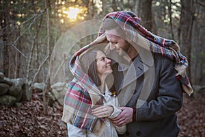 Romantic young couple under a blanket in the forest