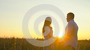Romantic young happy couple silhouette in golden wheat field at sunset. Woman and man hugging and kissing against