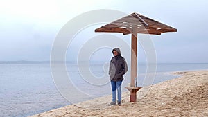 Romantic young man relaxing on the beach with , drinking hot tea or coffee from thermos. Calm and cozy evening.