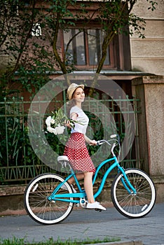 Romantic young nature on a blue retro bike stretches peonies