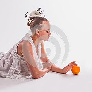 Romantic young woman lies on white background and touches ripe fresh orange