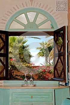 Romantical window with to champagne glasses. Oriental window with view to beautiful garden in Morocco