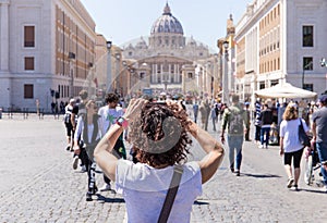 ROME, ITALY - APRIL 27, 2019: Young woman photographs the Saint Peter`s Basilica, Rome, Italy.