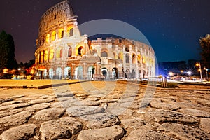Rome, Italy. Colosseum Also Known As Flavian Amphitheatre In Night. Calmness Night Time. Bright Blue Night Starry Sky