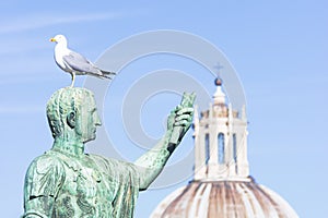 Statue of emperor Caesar Nervae August with gull on the head. Man taking selfie. Humor concept