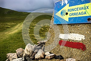 The Way Marking Post with Yellow Arrow Sign for Roncesvalles in the Pyrenean Mountains on the Camino photo