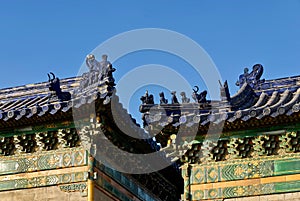The roof of an ancient Chinese temple with blue ceramic tiles and mythical figures. The temple roof against the blue sky. Temple